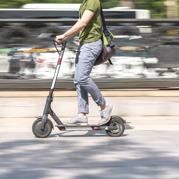 Man with a bag taking an electronic mobility device called an e-scooter as a means of electronic transportation